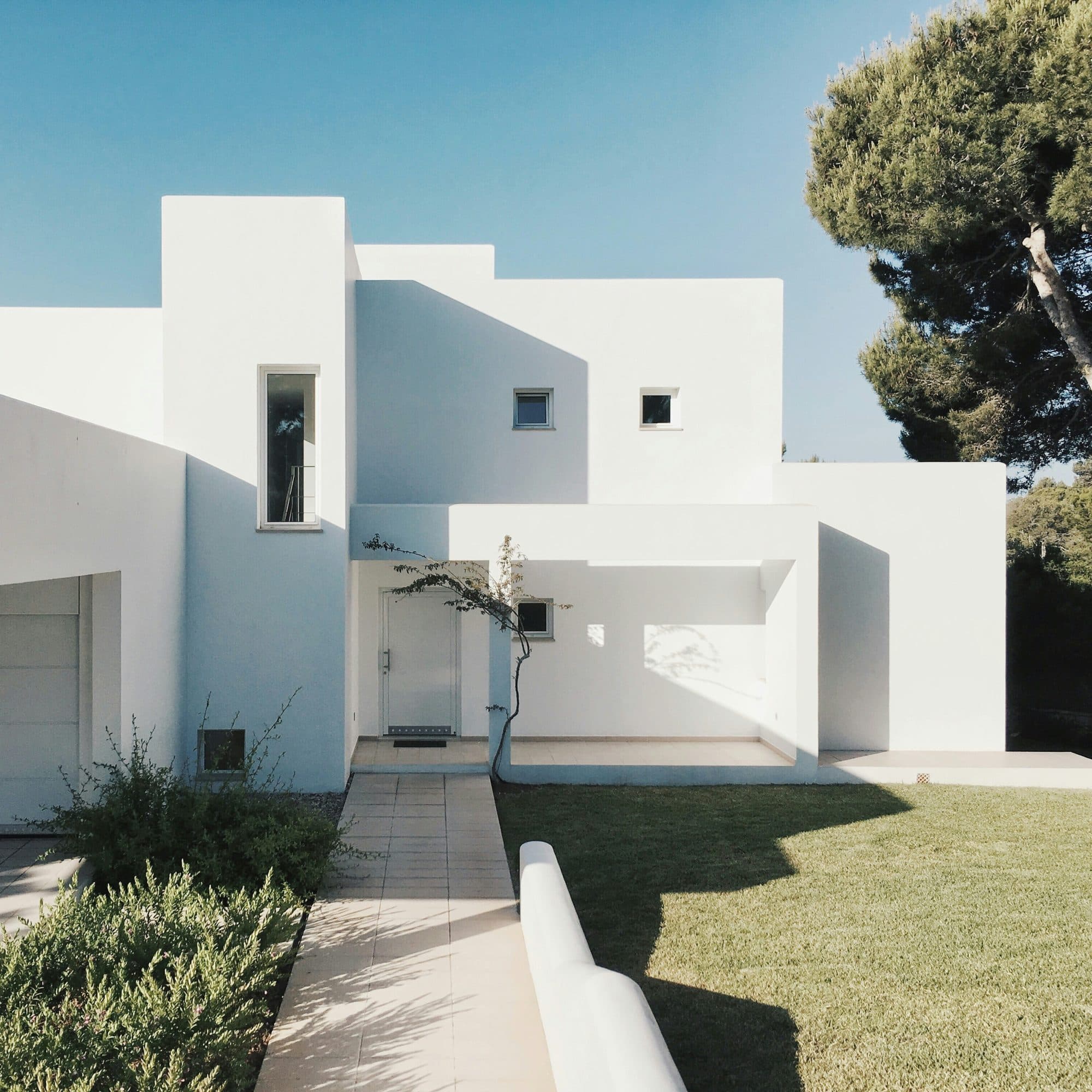 Modern white architectural home against a clear blue sky
